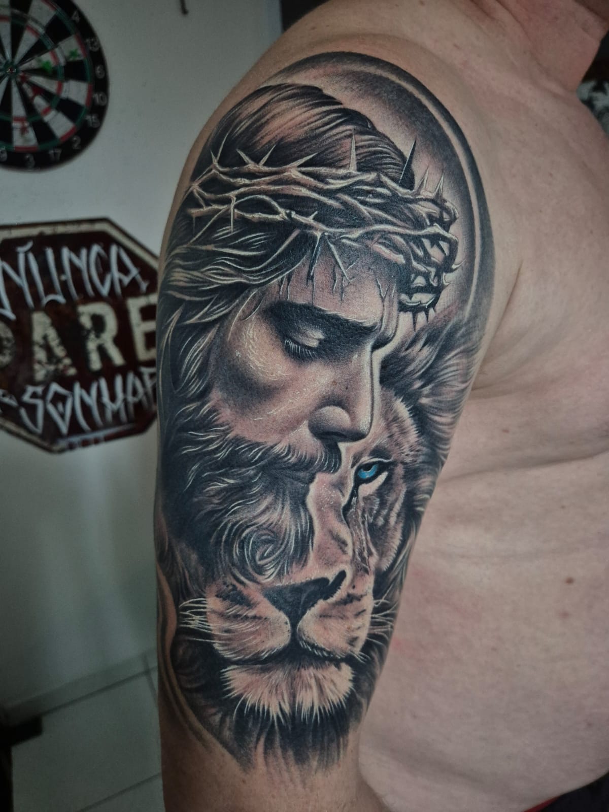 Tatuagem realista de Jesus com leão no braço