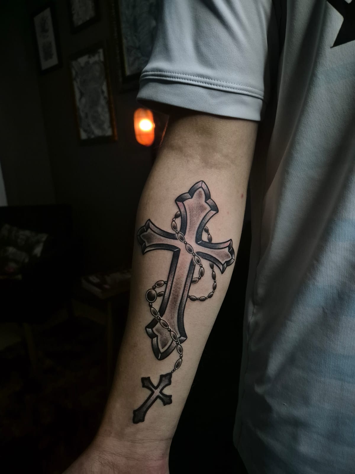 Tatuagem de cruz com terço no antebraço