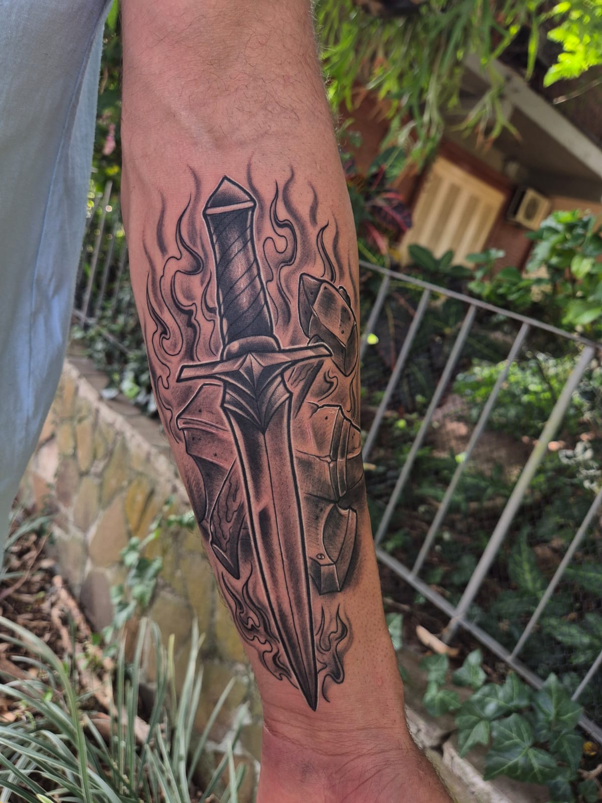 Tatuagem de adaga com chamas no antebraço